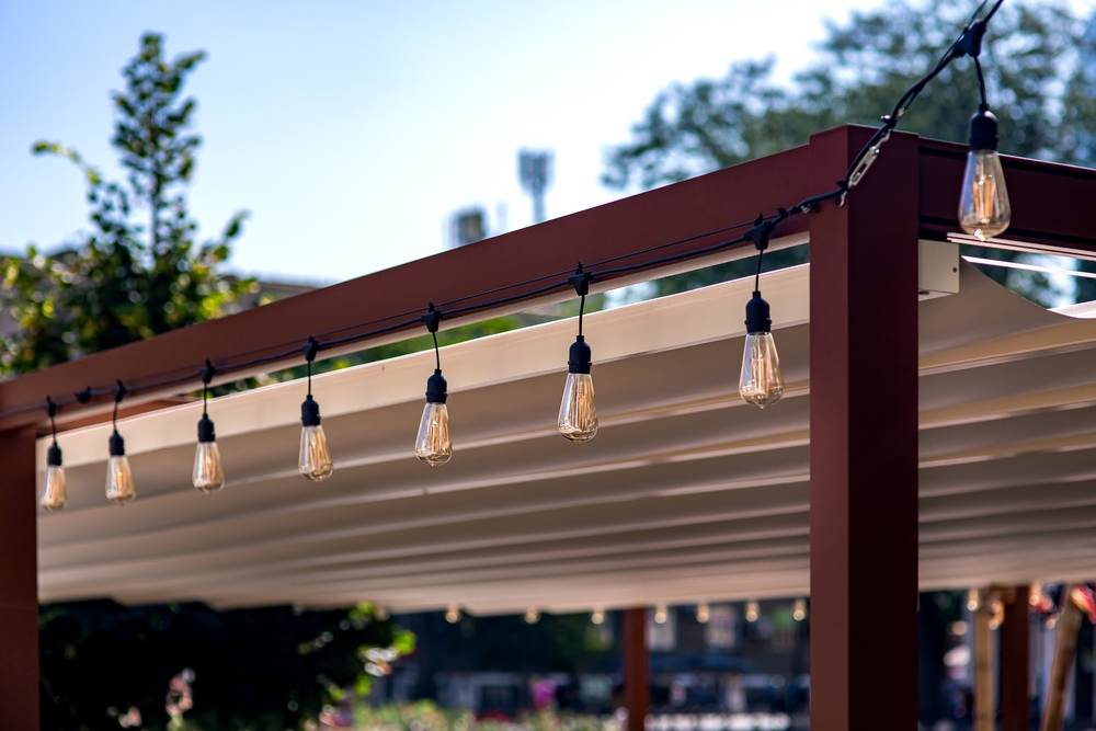 A patio awning with lights dangling from it.